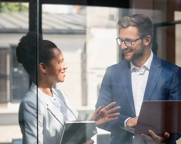 A photo of two coworkers discussing in a conference room