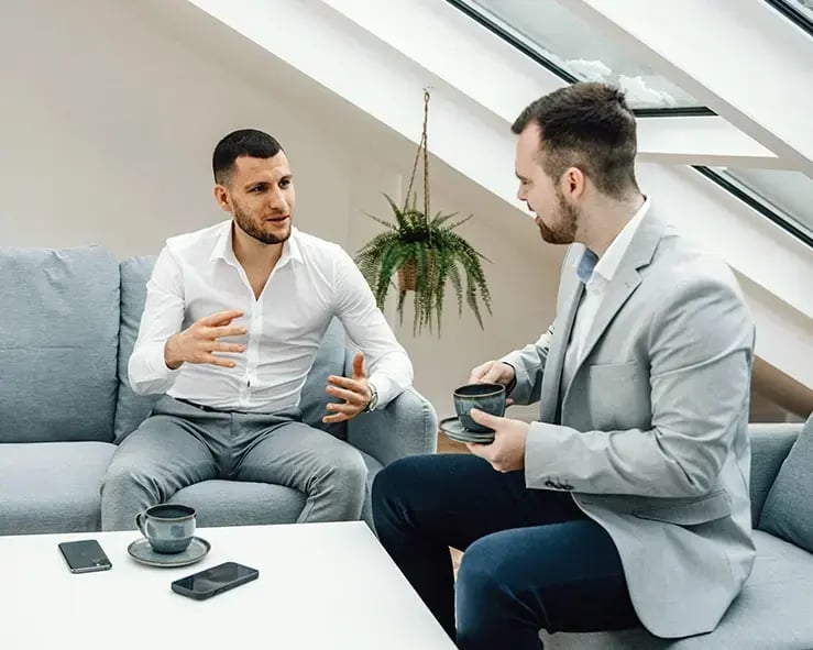 Photo of two businessmen sitting on couches and having a meeting