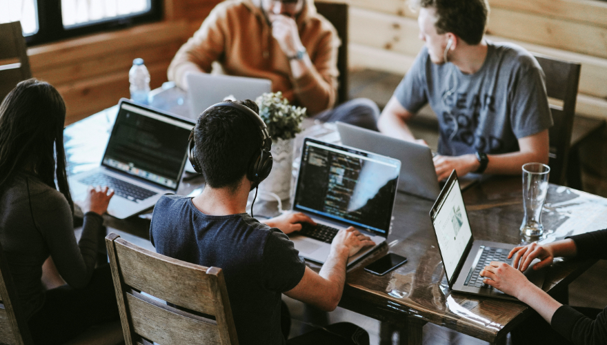 Five colleagues working on coding projects and using laptops.