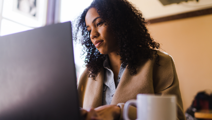 Woman on her laptop with a coffee cup next to her