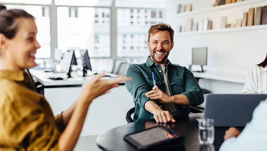 Group of people laughing while sitting in an office meeting