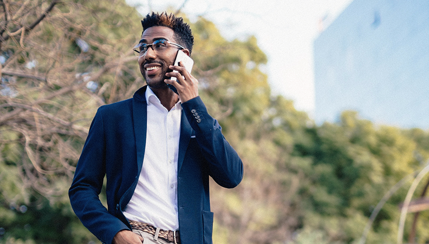 Photo of a man walking outside will taking a call on him cellphone