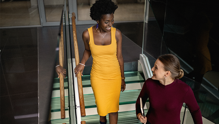 A photo of two colleagues talking and walking down the stairs