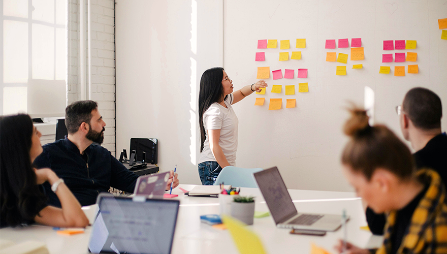 Photo of a team working in an office with sticky notes on the wall