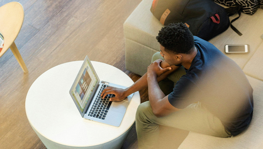 Photo of a man sitting on a couch and working on a laptop