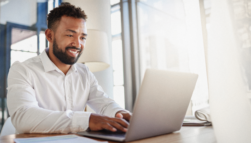 Photo of a man at a laptop watching a webinar